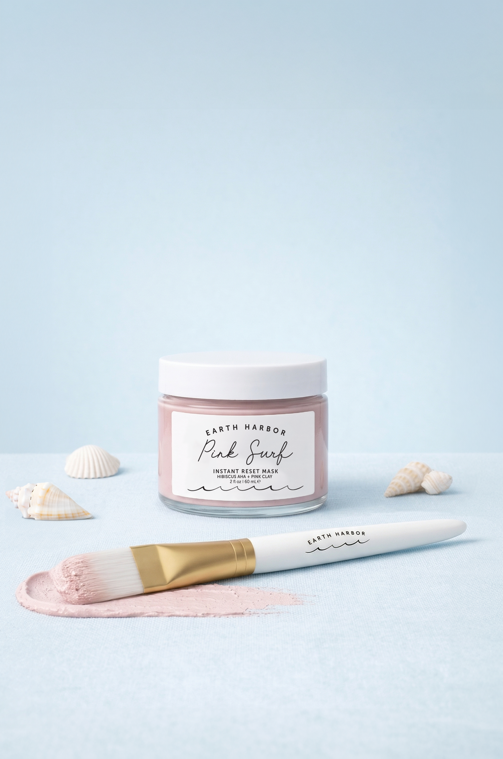 Pink surf instant mask with a brush and shells on a light blue background